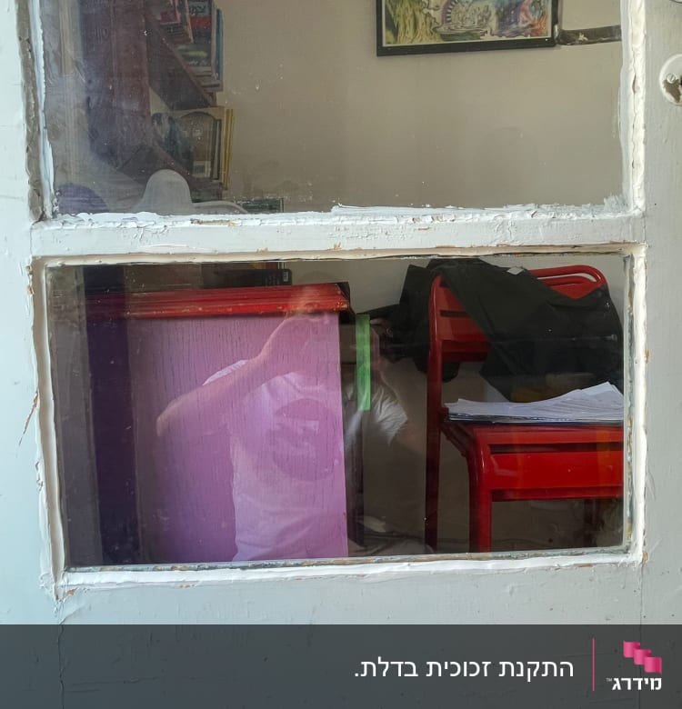 דלת זכוכית עם השתקפות של אדם בחולצה לבנה